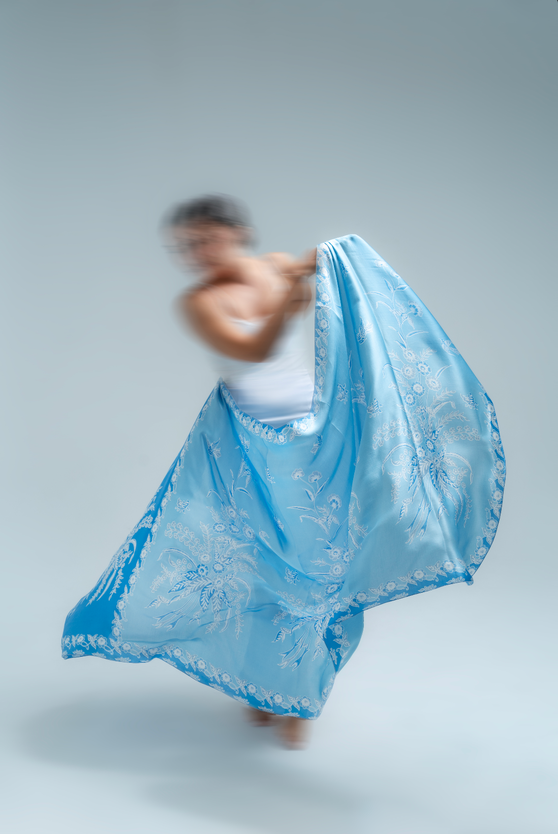 Person holding a blue batik sarong against a plain background