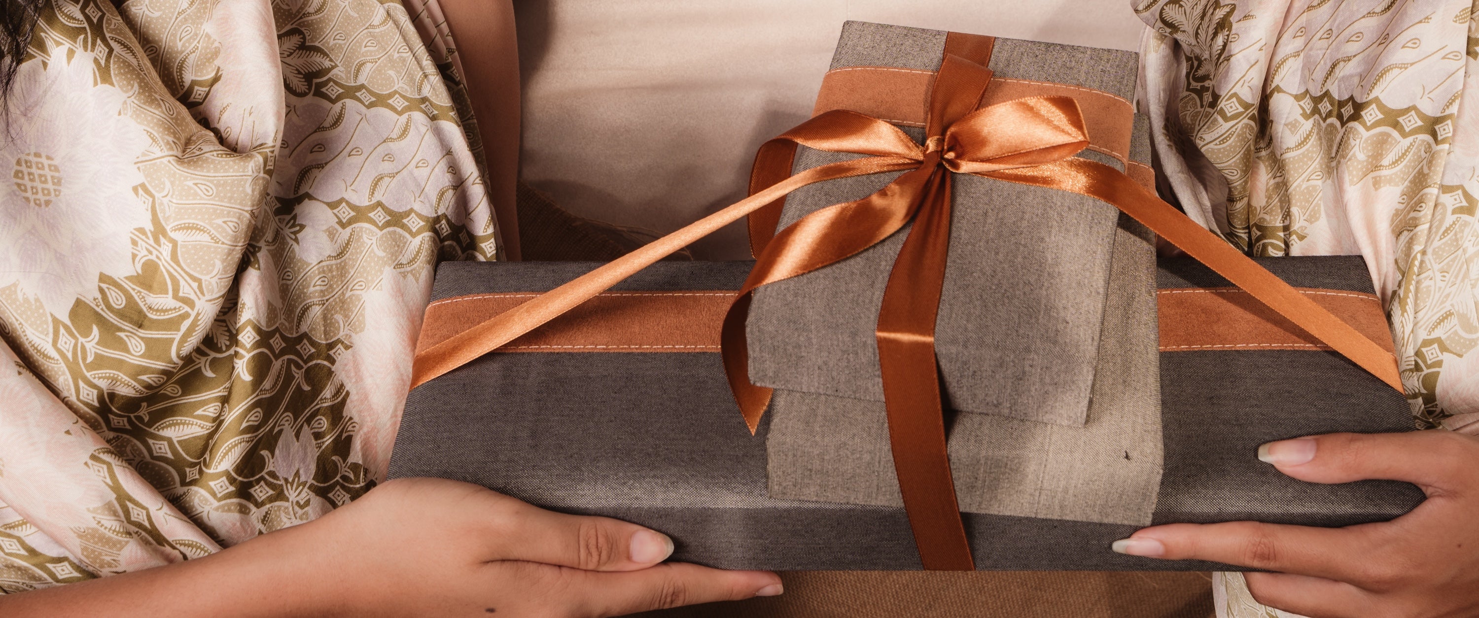 A woman holding a gift wrapped in brown paper.