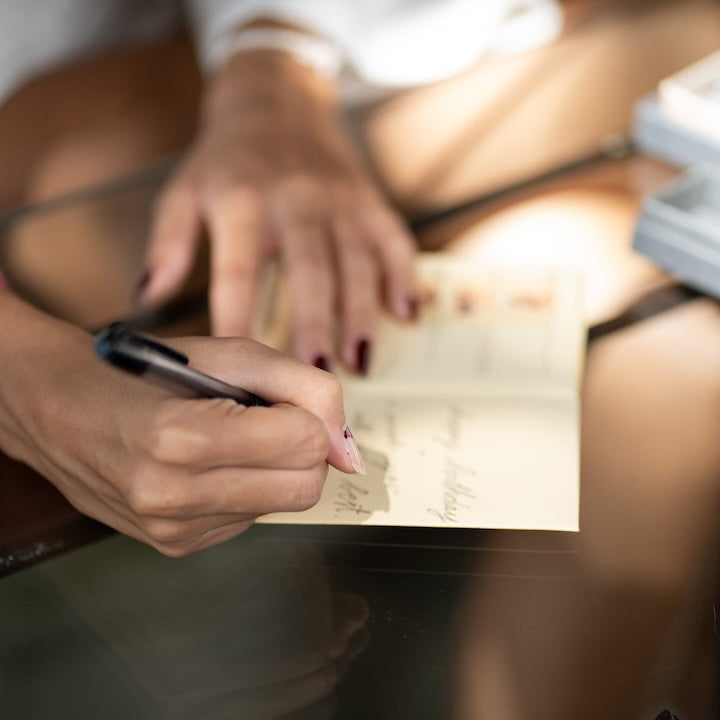  A woman sitting at a desk, writing on a piece of paper with a pen.