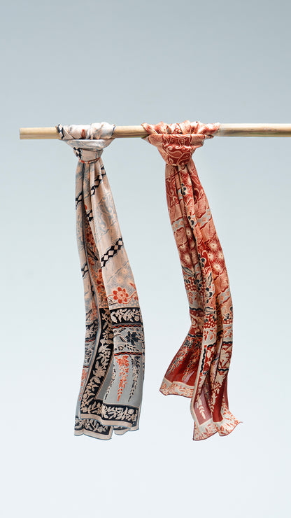 Two lengko batik scarves hanging on a rod against a light gray background