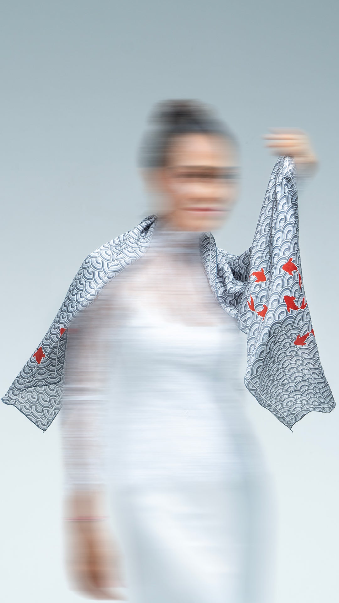 Person wearing a scarf garment with fish and Japanese patterns on a plain background