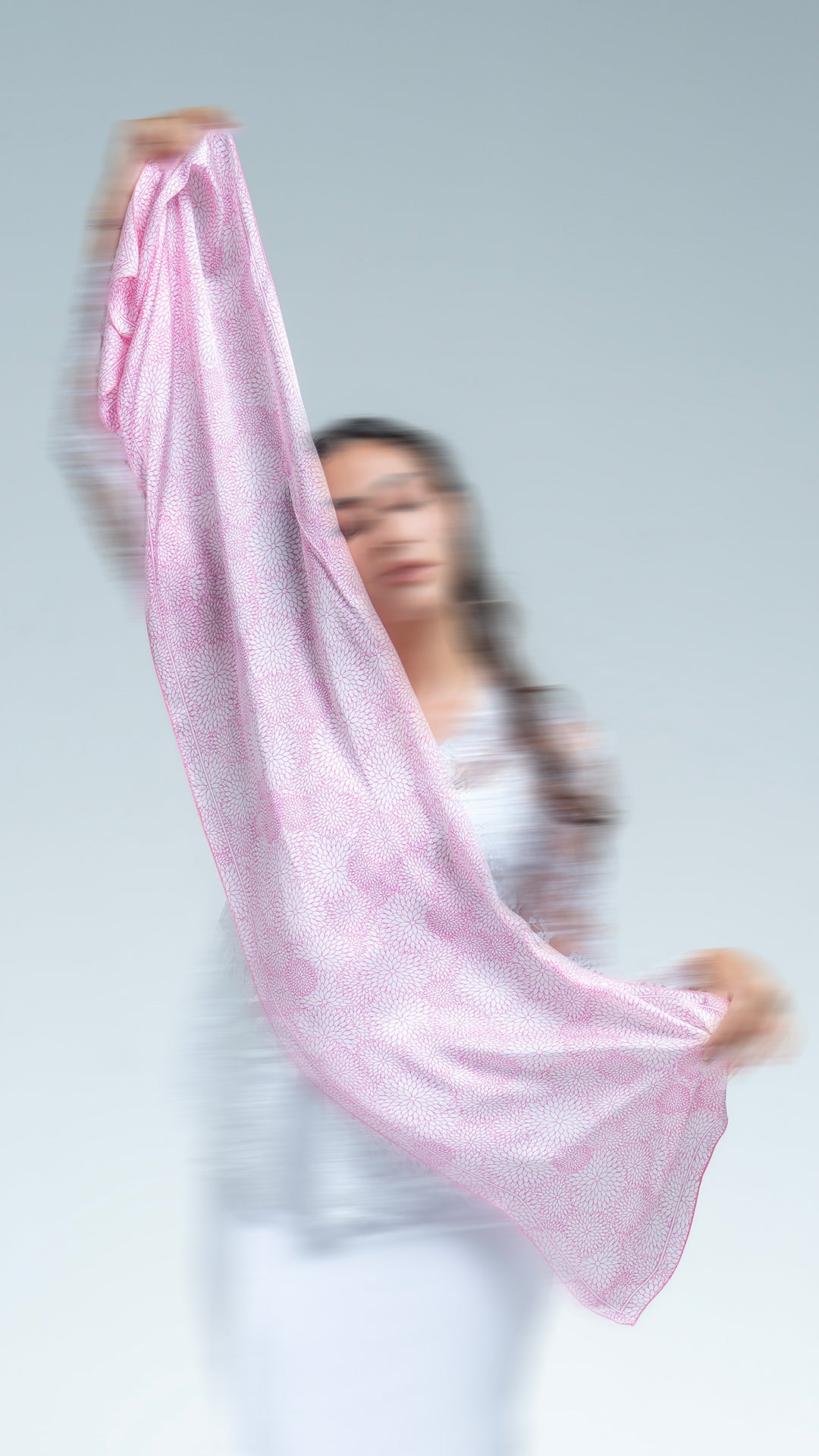 Woman holding a blossom pink scarf against a white background