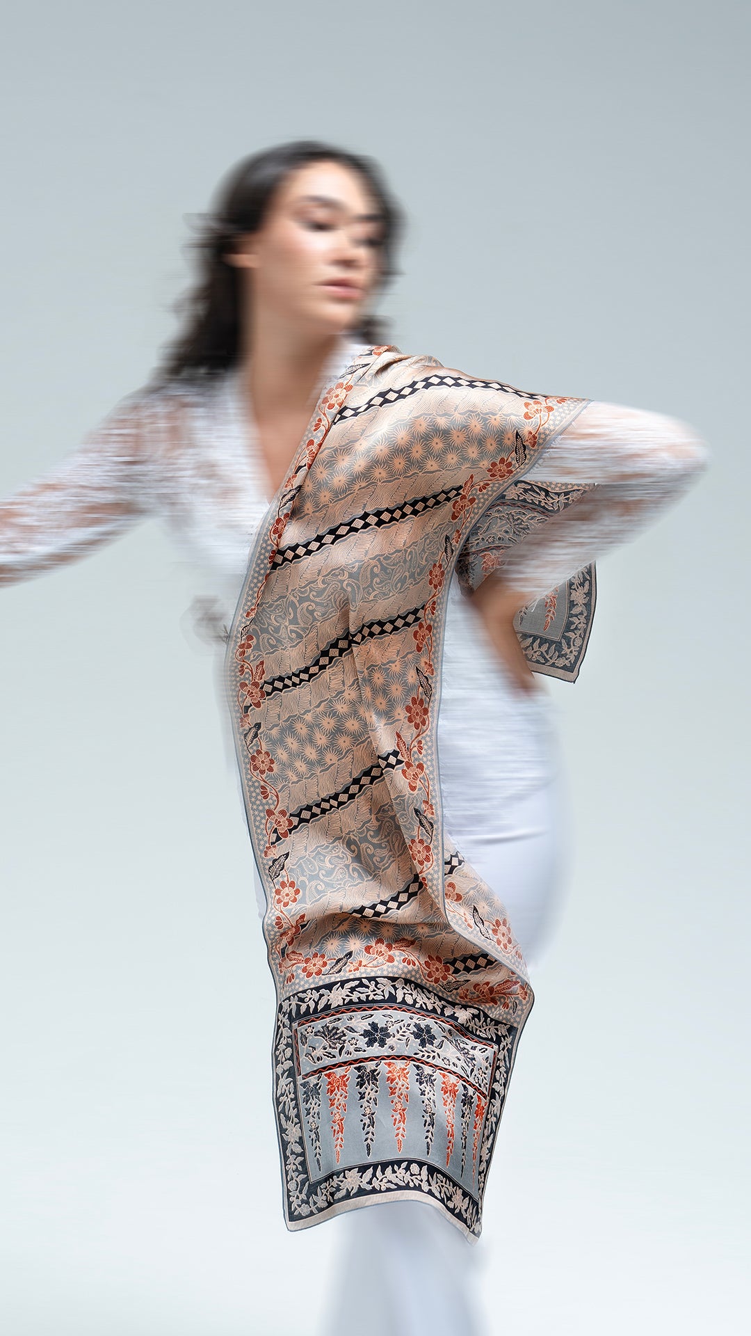 Woman wearing a lengko batik scarf on a plain background