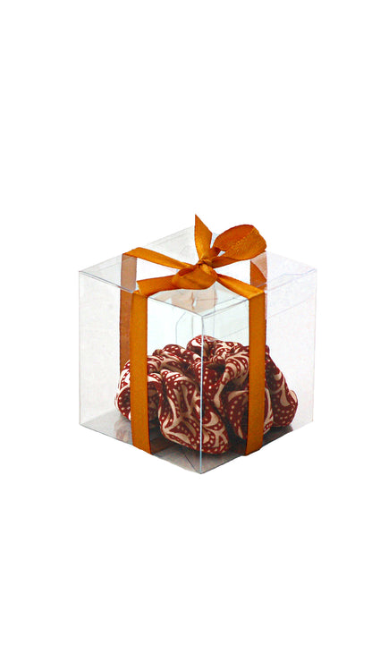 Clear gift box with a red and gold patterned item inside and an orange ribbon on a white background.